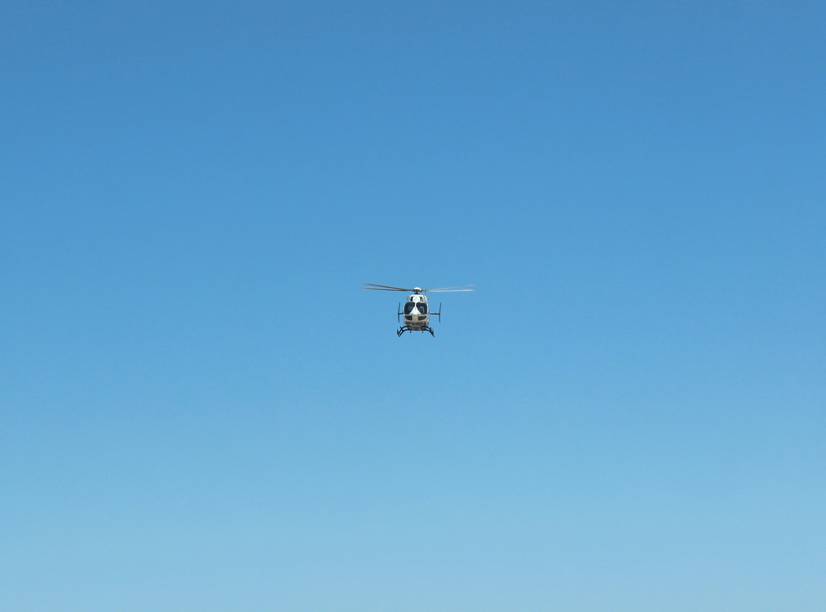 white and black drone flying under blue sky during daytime, 