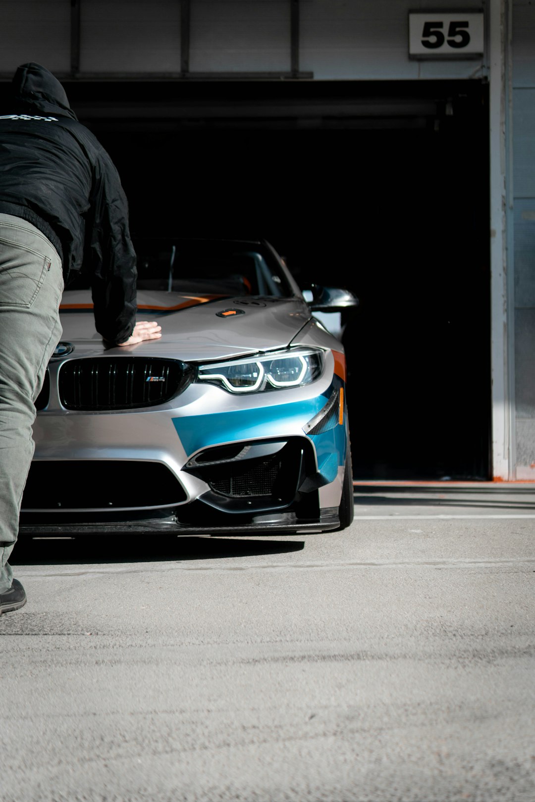 man in black jacket and gray pants standing beside white and black bmw car