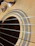 Close-up of a pair of sleek Kyrot earplugs resting next to a guitar on a wooden table.