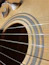 Close-up of a pair of sleek Kyrot earplugs resting next to a guitar on a wooden table.