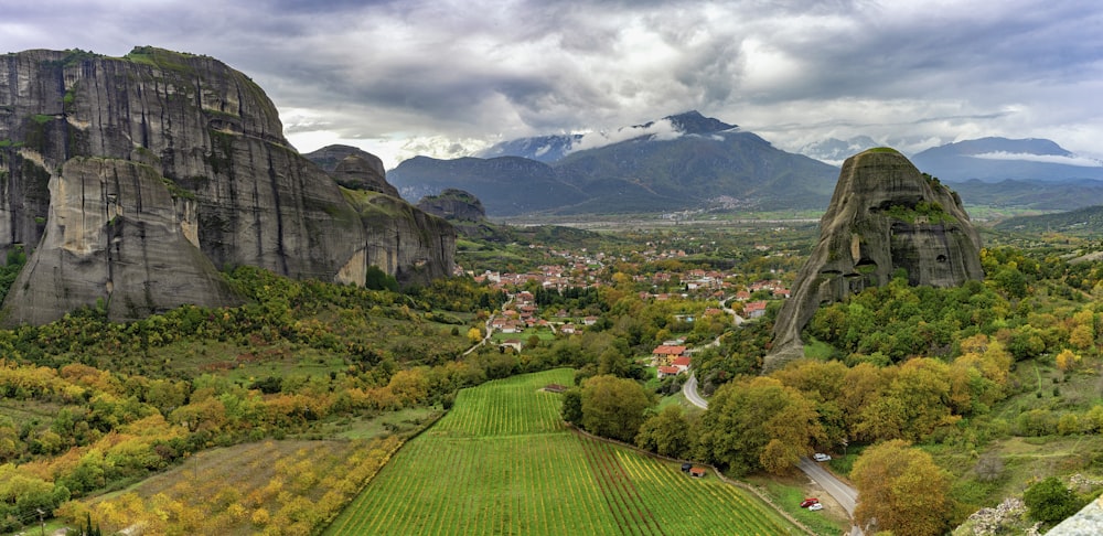 green grass field near mountain under white clouds during daytime