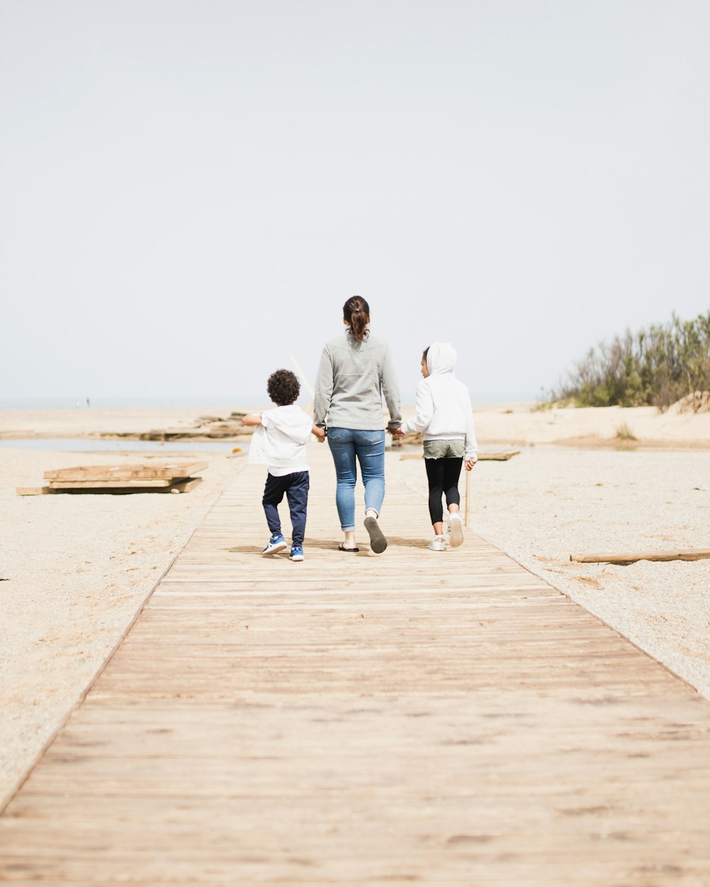 man and woman walking on brown wooden dock during daytime