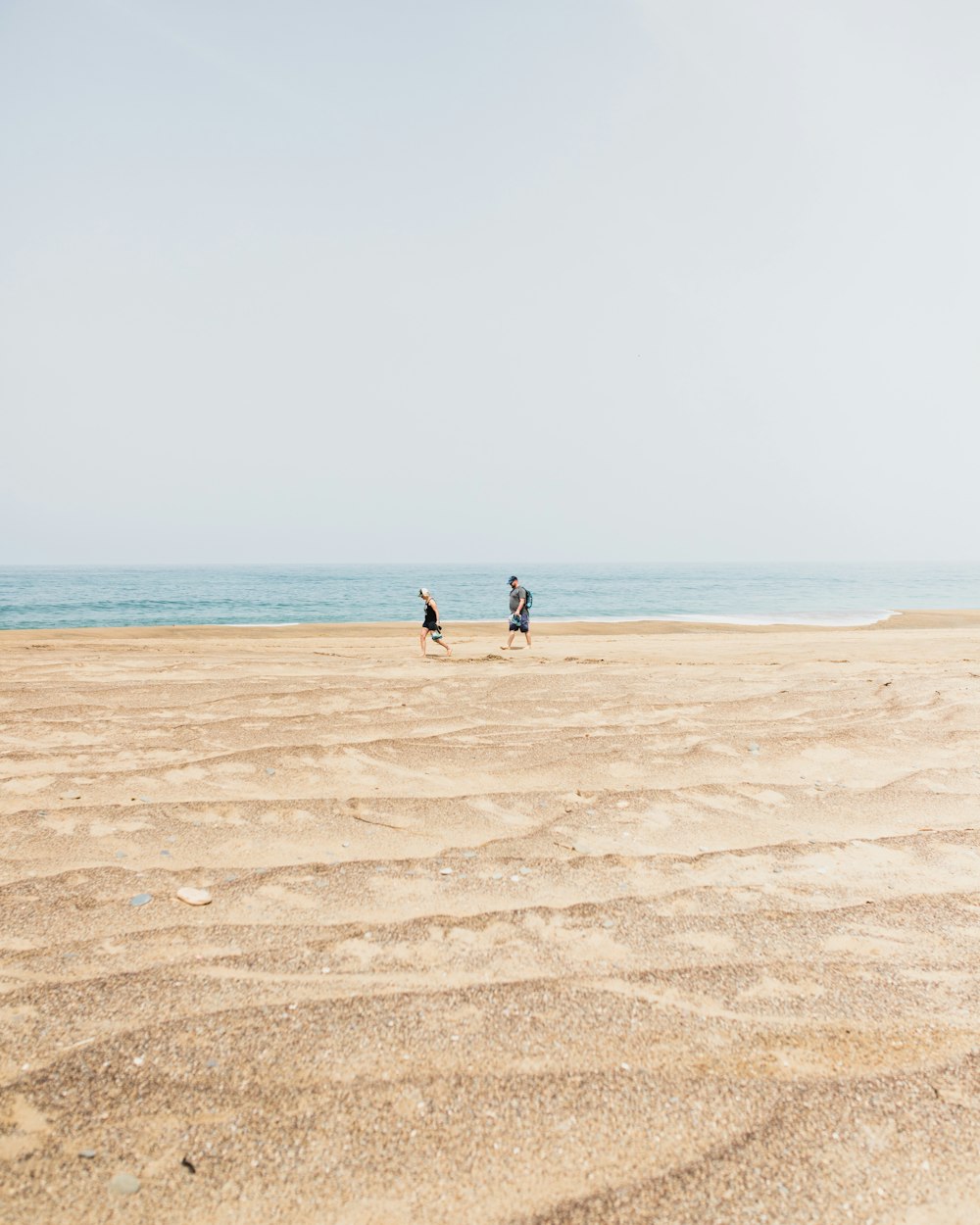 낮에는 바다 근처의 갈색 모래 위를 걷는 2 명
