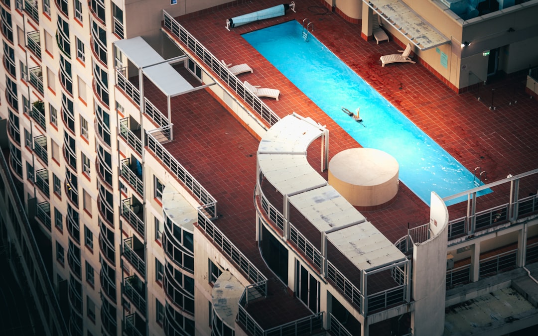blue swimming pool beside white and brown concrete building