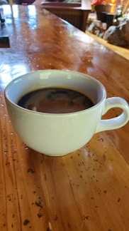 A cozy, stylish coffee mug with a sleek matte finish resting on a wooden table beside a sunlit window.