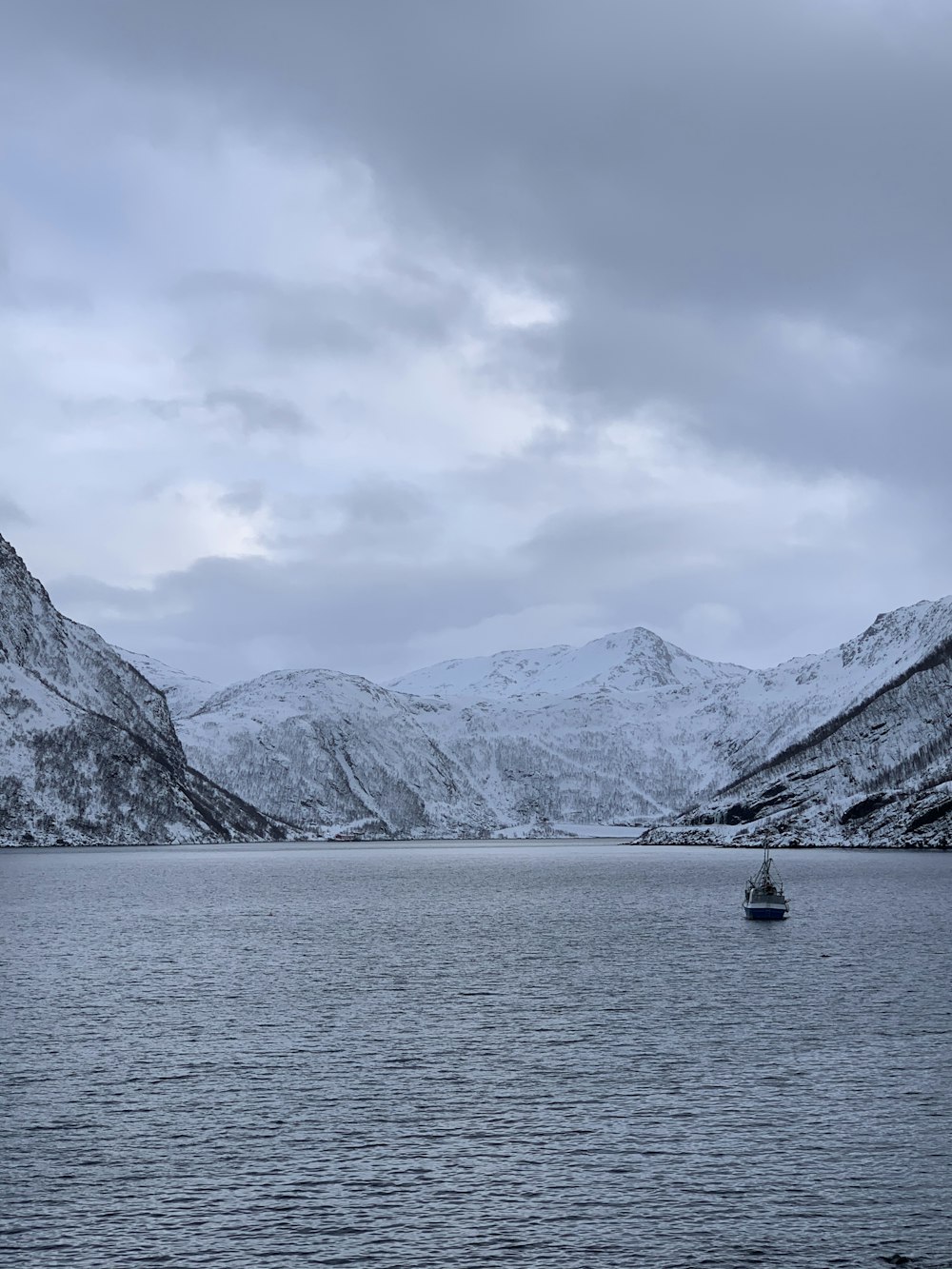 person riding on boat on sea near snow covered mountain during daytime