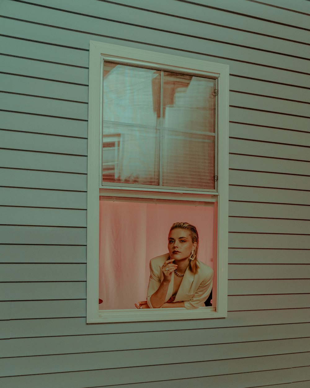 woman in white tank top standing in front of white wooden window