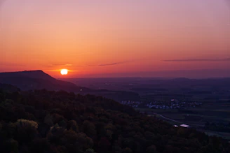 A vibrant sunset over the rolling hills of Sumba with traditional houses in the foreground