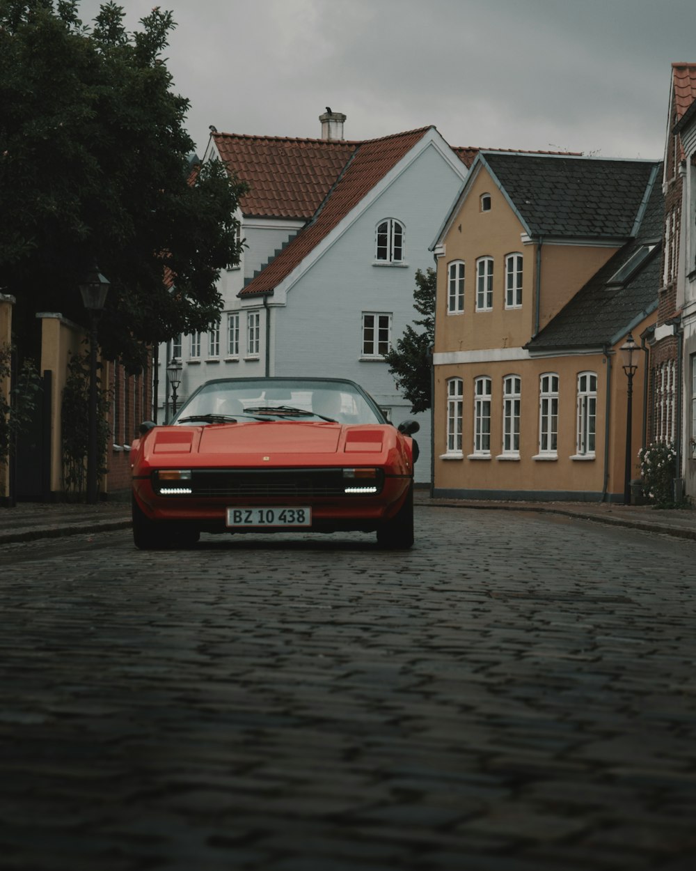 red car parked beside brown concrete building during daytime