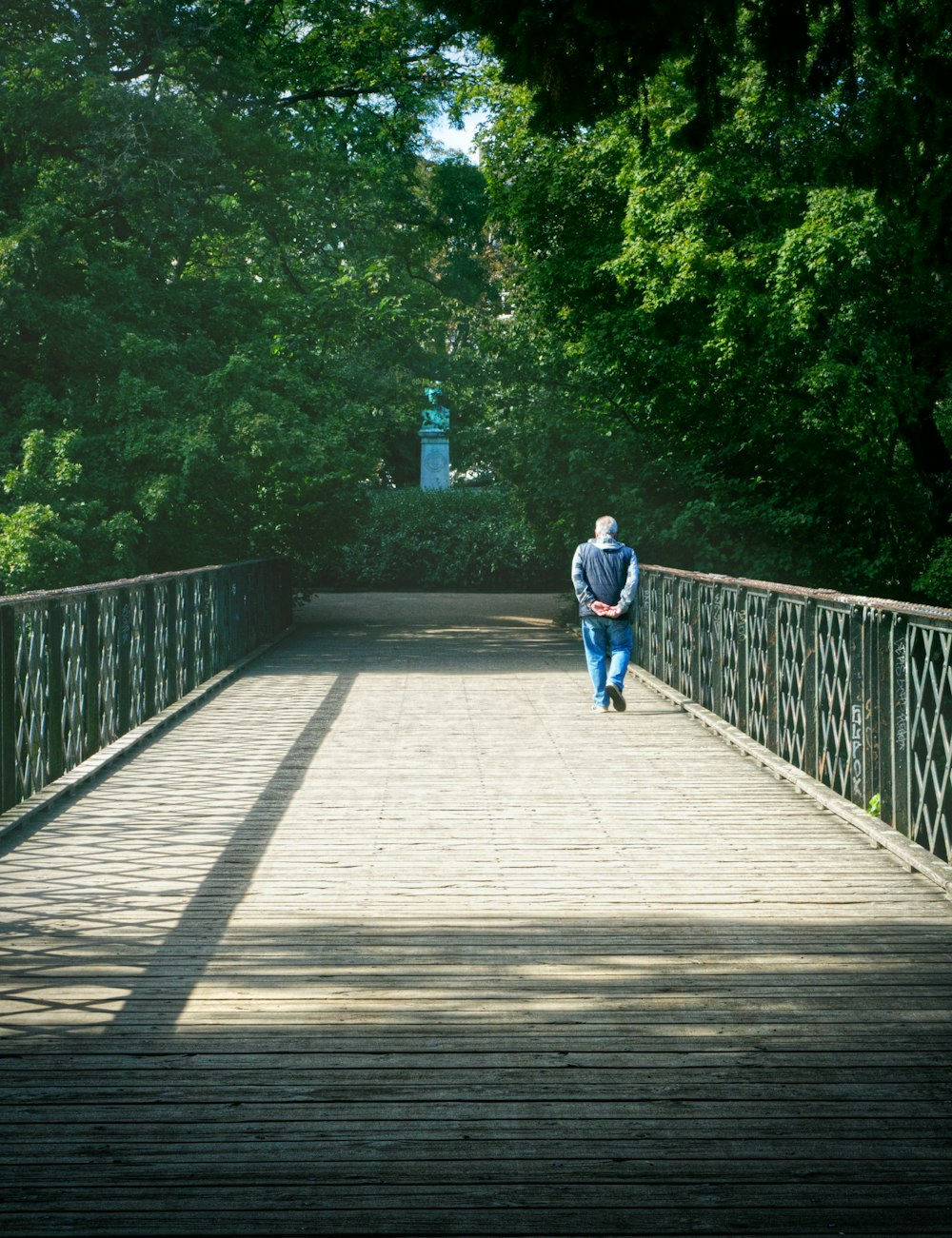 man in blue shirt walking on wooden bridge