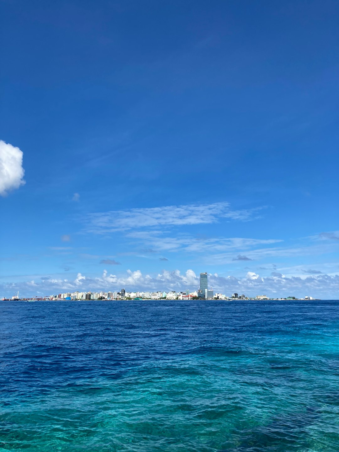 city skyline across the sea under blue and white cloudy sky during daytime