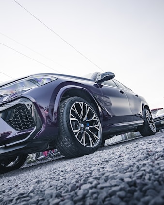 Side angle of a black SUV with shiny rims on a gravel road.