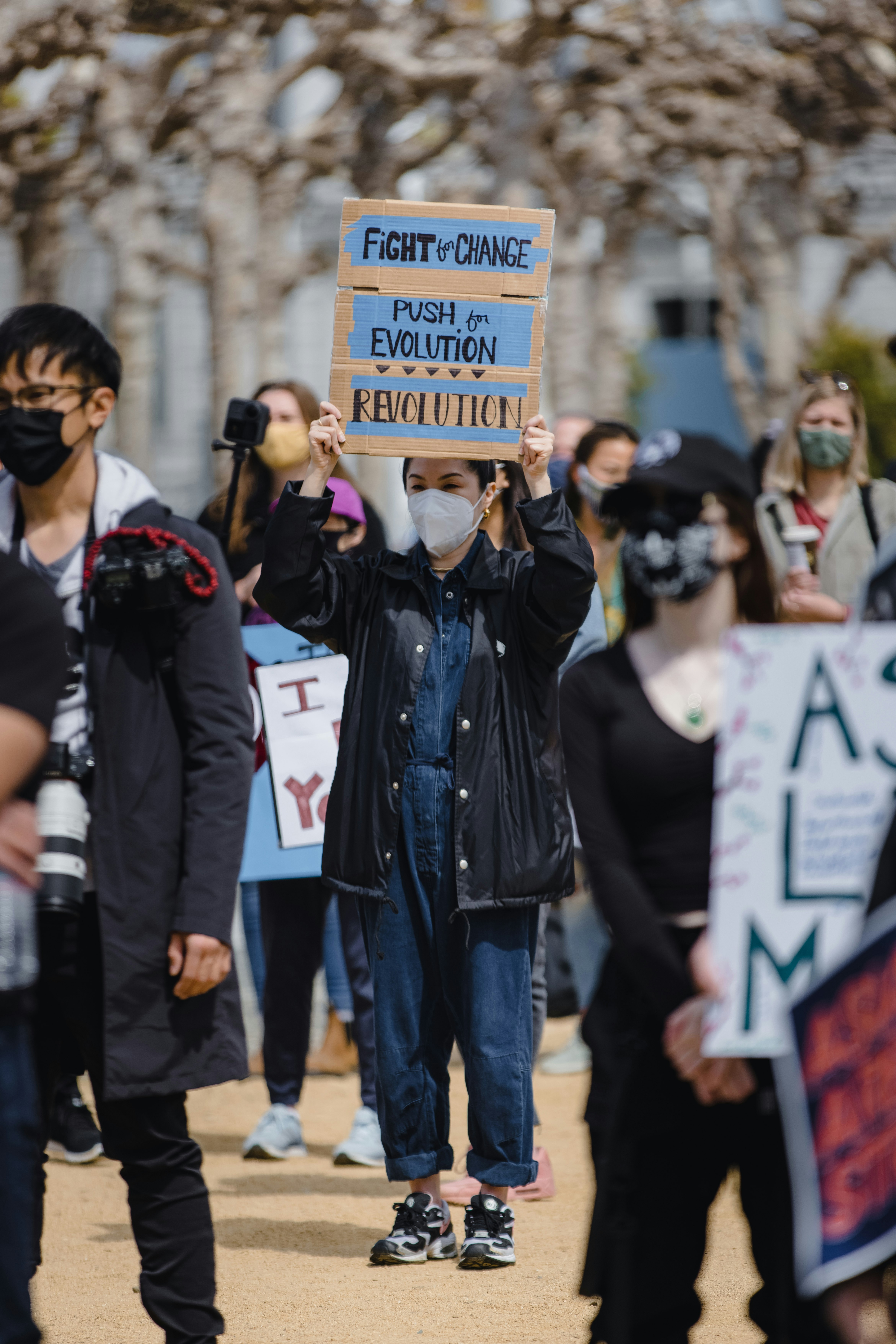 man in black leather jacket holding brown wooden signage