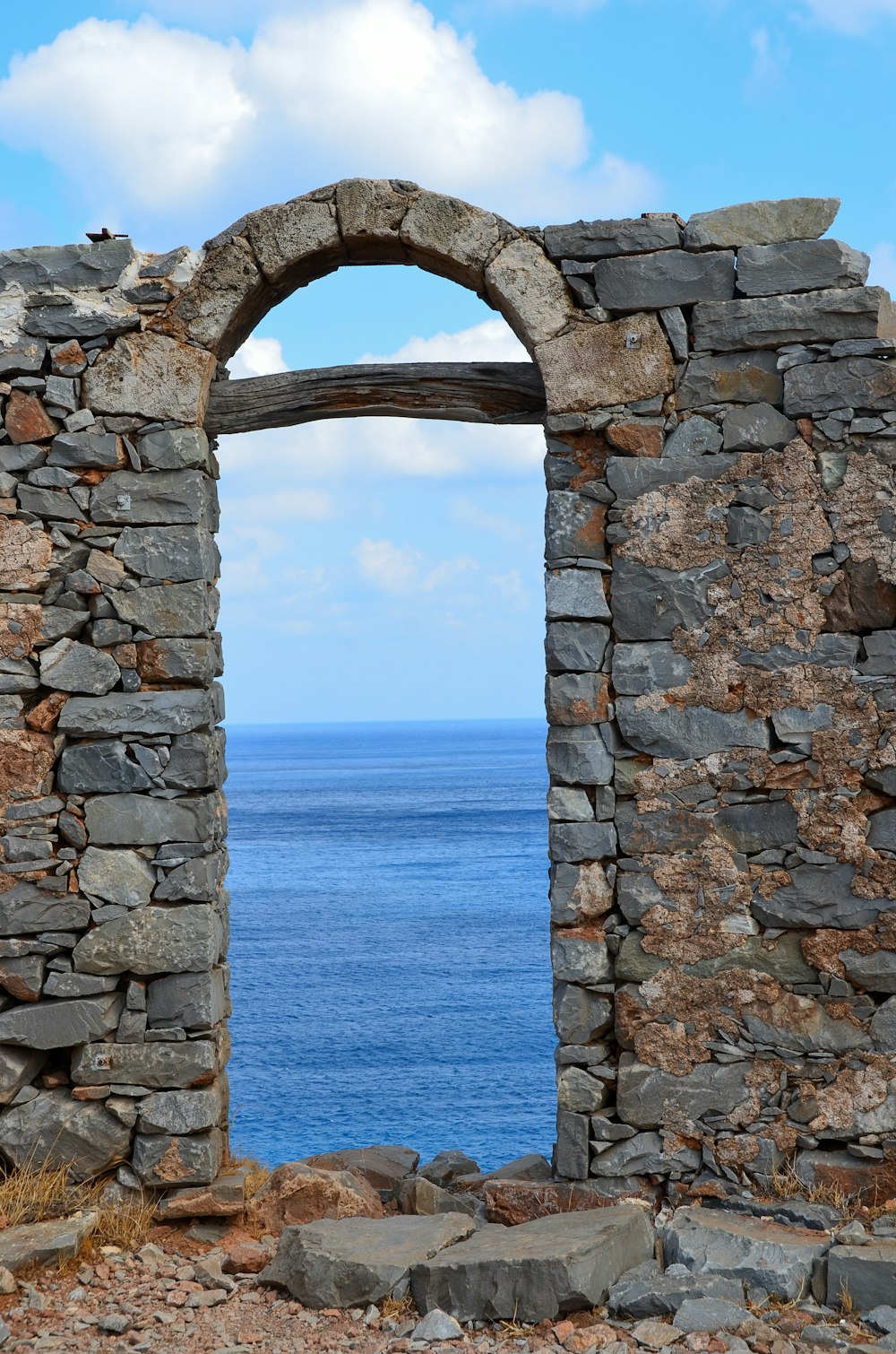 Arco di cemento grigio vicino al mare blu durante il giorno