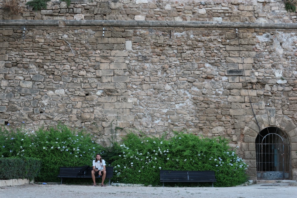 2 women standing beside brown brick wall during daytime