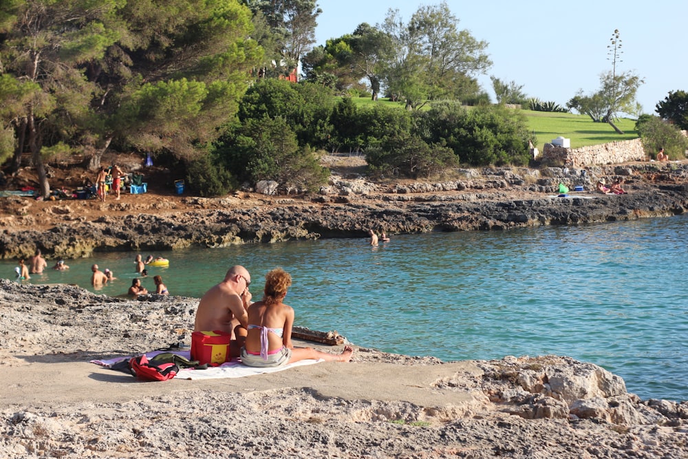 woman in pink bikini lying on beach sand near body of water during daytime