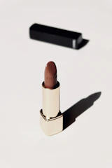 Sophisticated black and gold lipstick and foundation set with soft natural light.