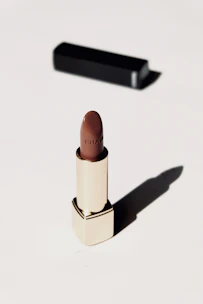 Sophisticated black and gold lipstick and foundation set with soft natural light.