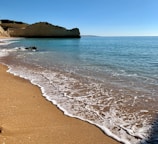 Golden sand beach with gentle waves under a clear blue sky at Sibale.