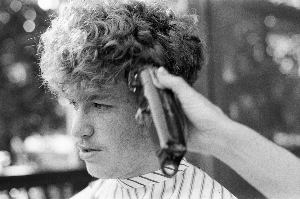 man in white and black stripe shirt holding hair clipper