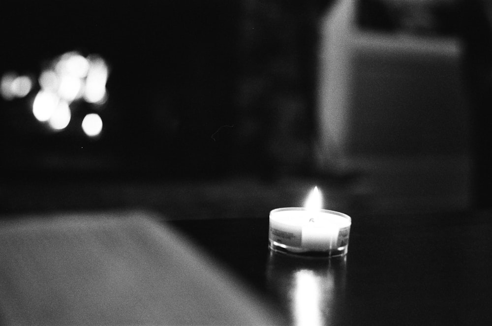 Foto en escala de grises de una vela encendida