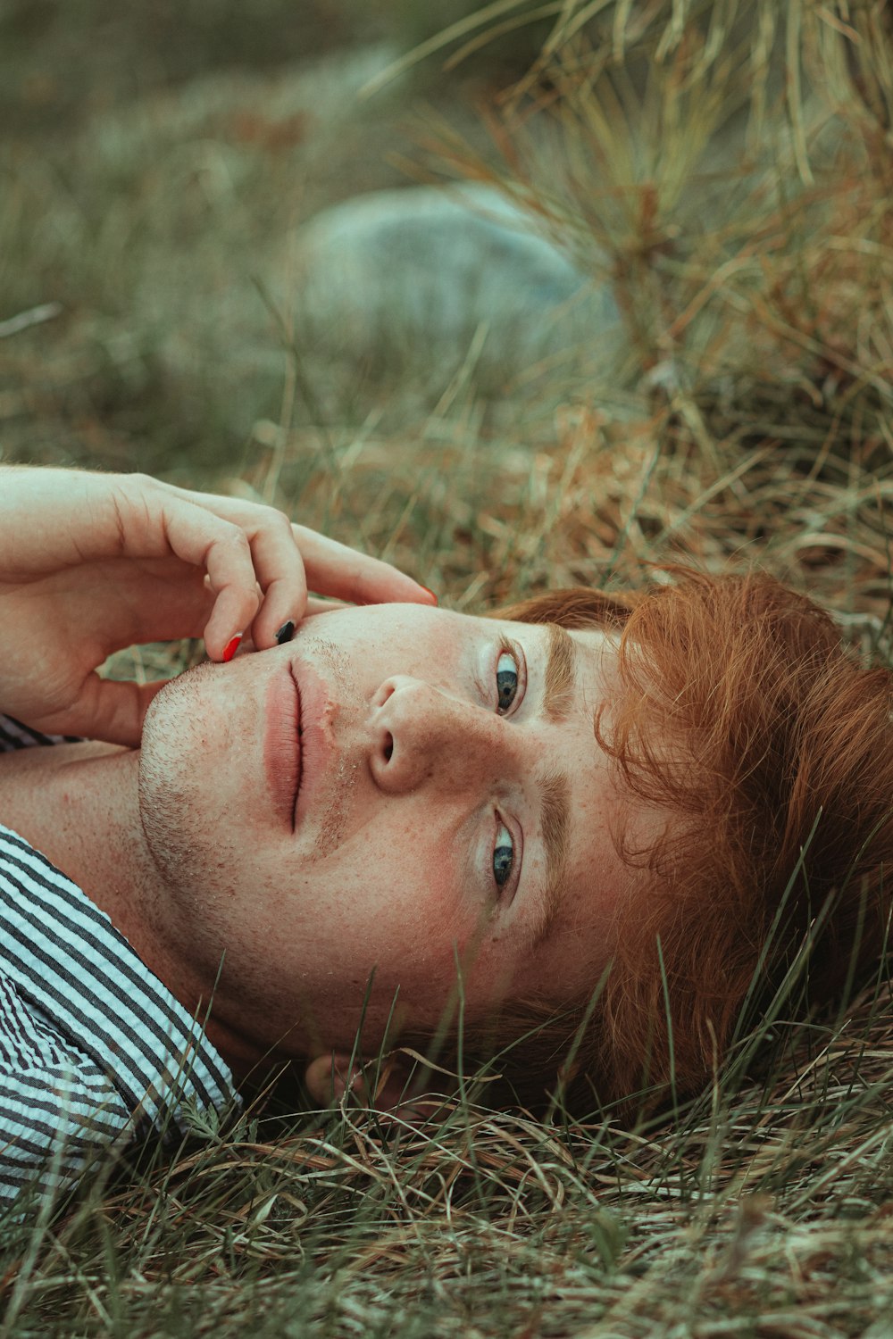 woman in white and black stripe shirt lying on brown grass field