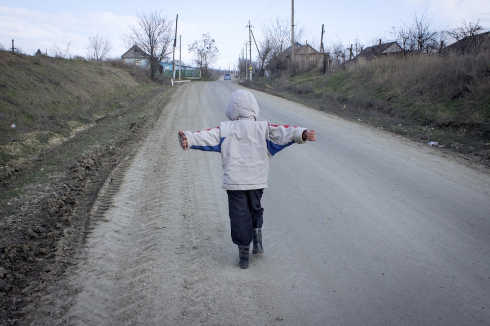 man in white jacket walking on road during daytime