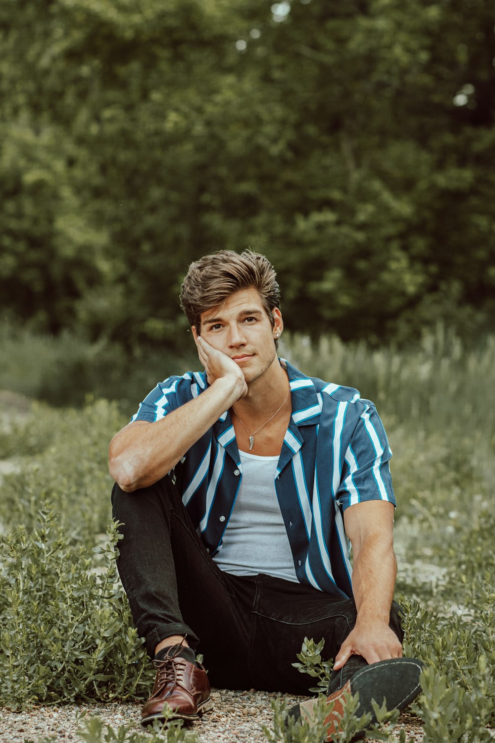 man in blue and white stripe polo shirt sitting on grass field