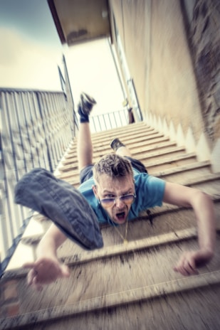 A person mid-fall while trying to catch a frisbee, with a surprised expression.
