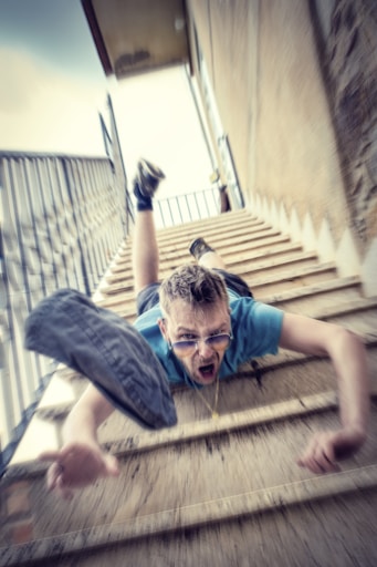 man in blue t-shirt and blue denim shorts sitting on concrete stairs during daytime
