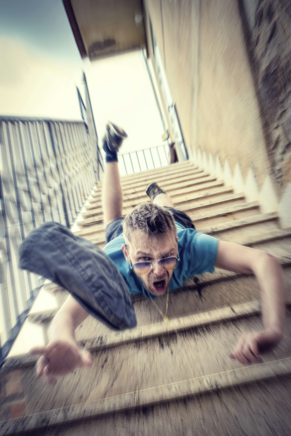 Homme en t-shirt bleu et short en jean bleu assis sur des escaliers en béton pendant la journée