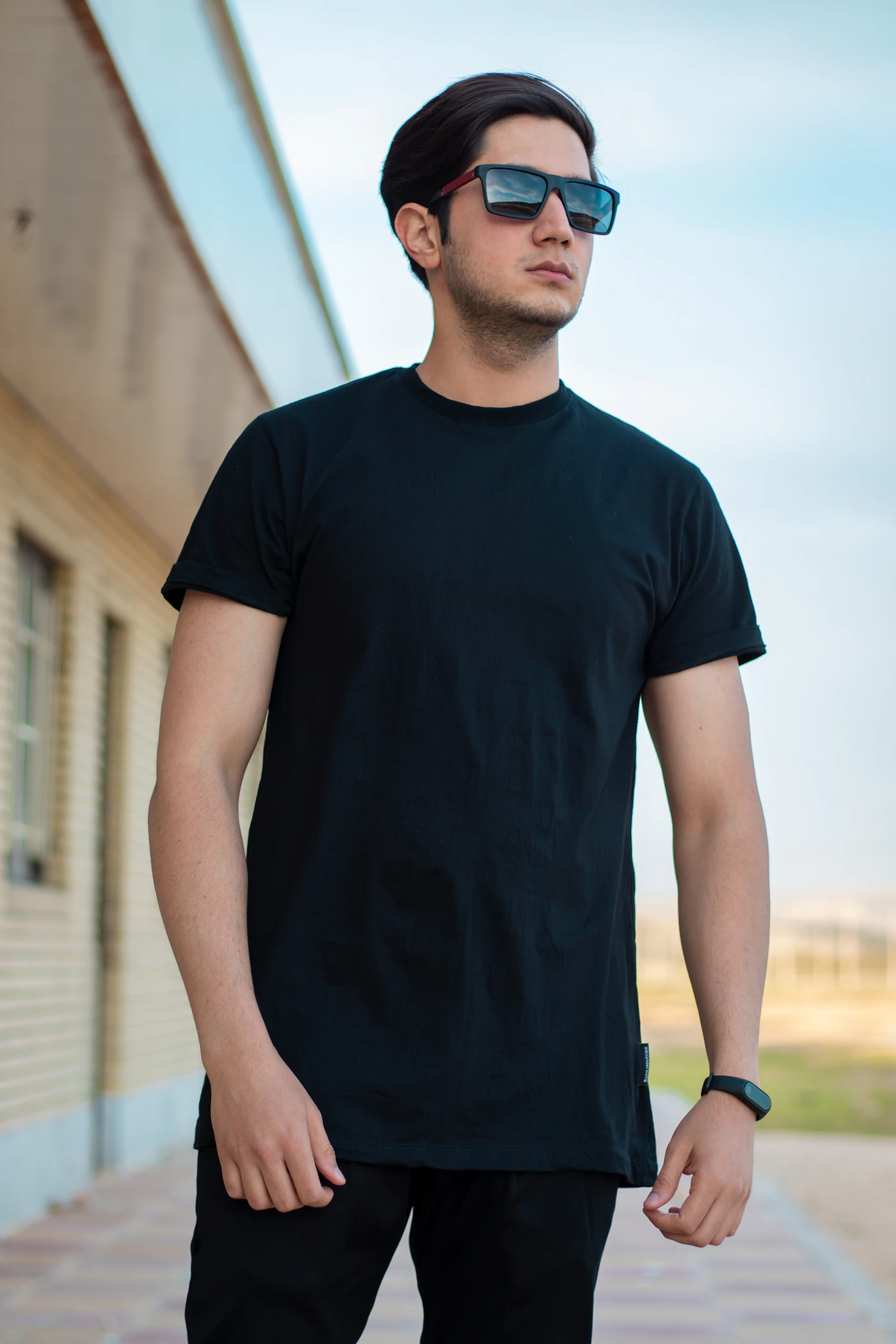 Man in a fitted black t-shirt and sunglasses outdoors