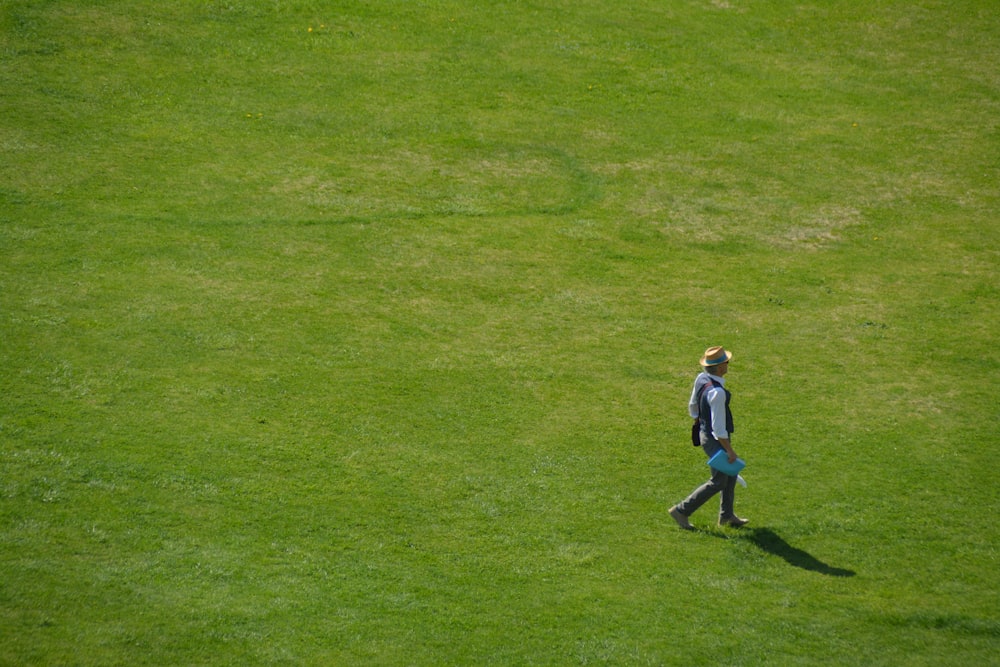 boy in blue shirt and blue denim jeans walking on green grass field during daytime