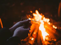 Hands holding a glowing fire starter ready to light a campfire.