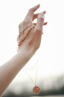 A woman’s hand adorned with a delicate, artistic intencyjny jewelry piece against a minimalist background
