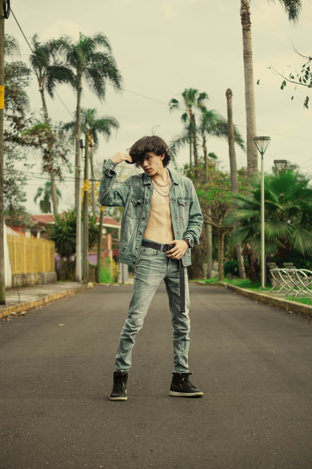 man in gray jacket and blue denim jeans standing on gray concrete road during daytime