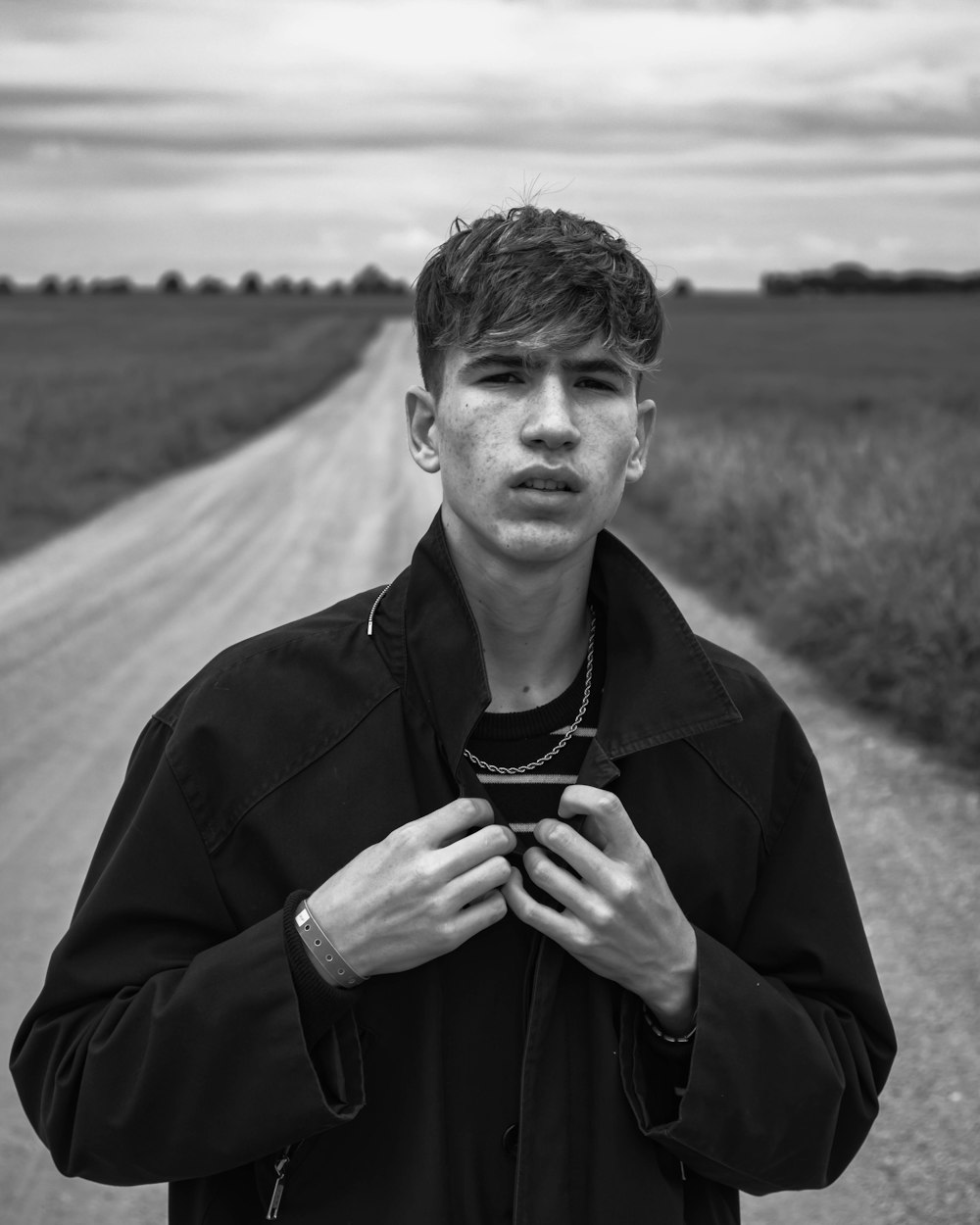 man in black coat standing on field in grayscale photography