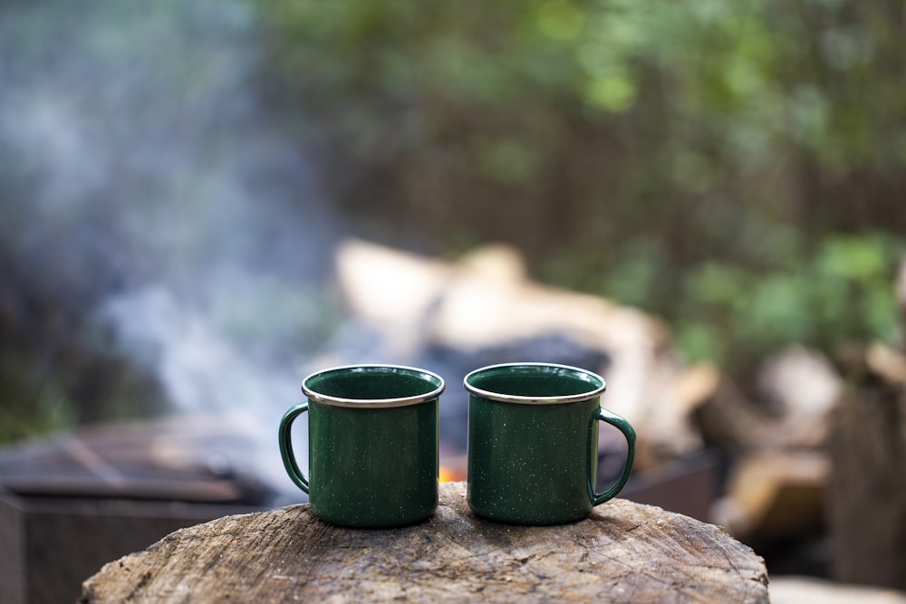 2 tasses en céramique verte sur bûche de bois marron