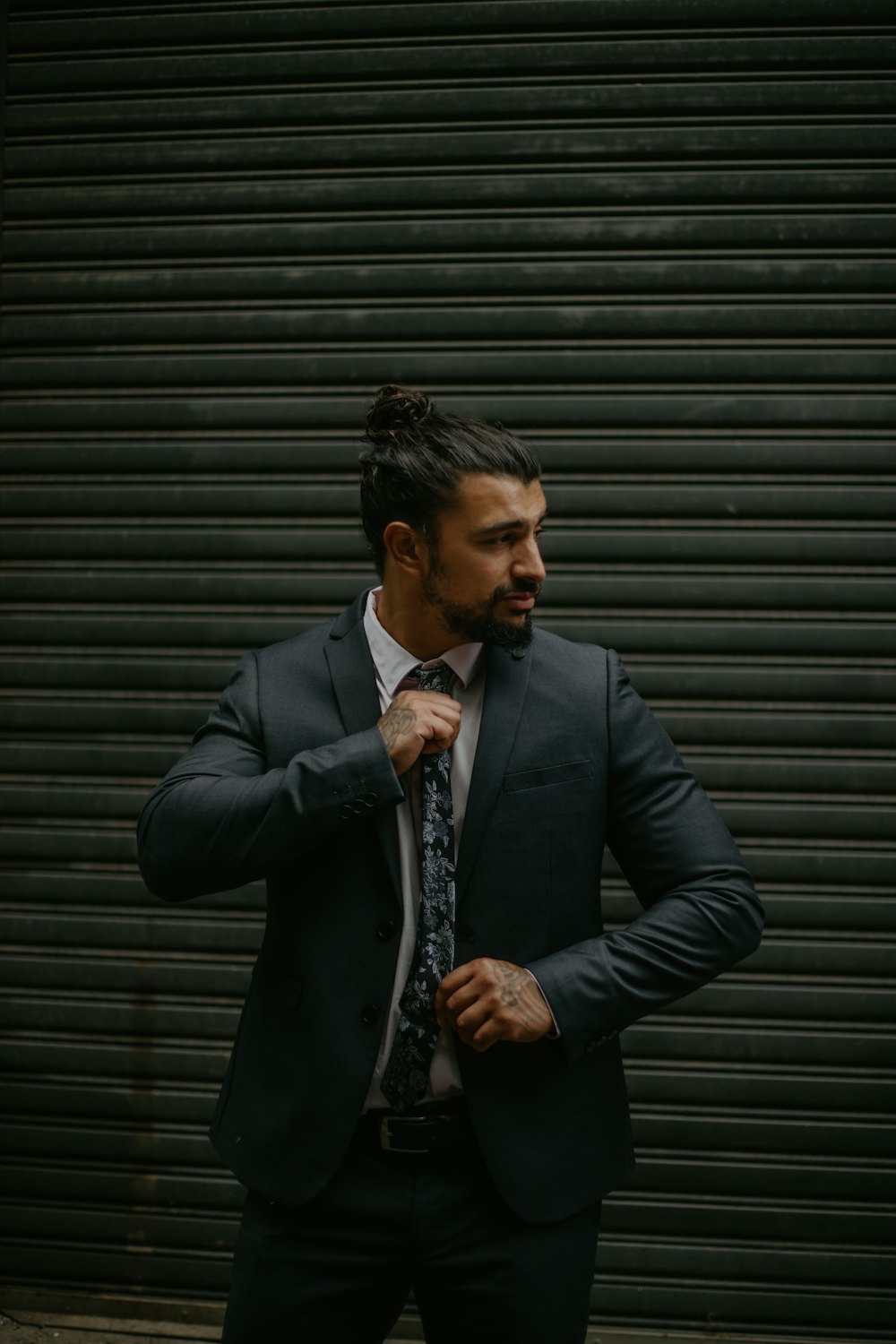 man in black suit jacket standing near roll up door