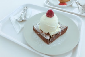 A slice of no egg brownie topped with fresh raspberries and a drizzle of chocolate sauce