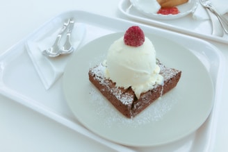 A slice of no egg brownie topped with fresh raspberries and a drizzle of chocolate sauce