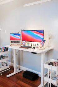 A sleek adjustable standing desk in a bright, modern home office.