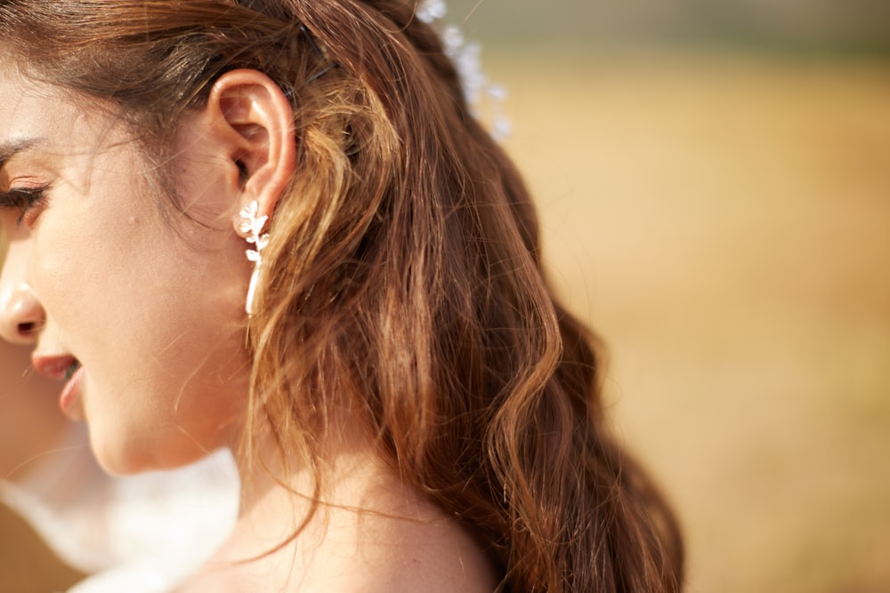 woman in white tank top wearing silver flower earrings