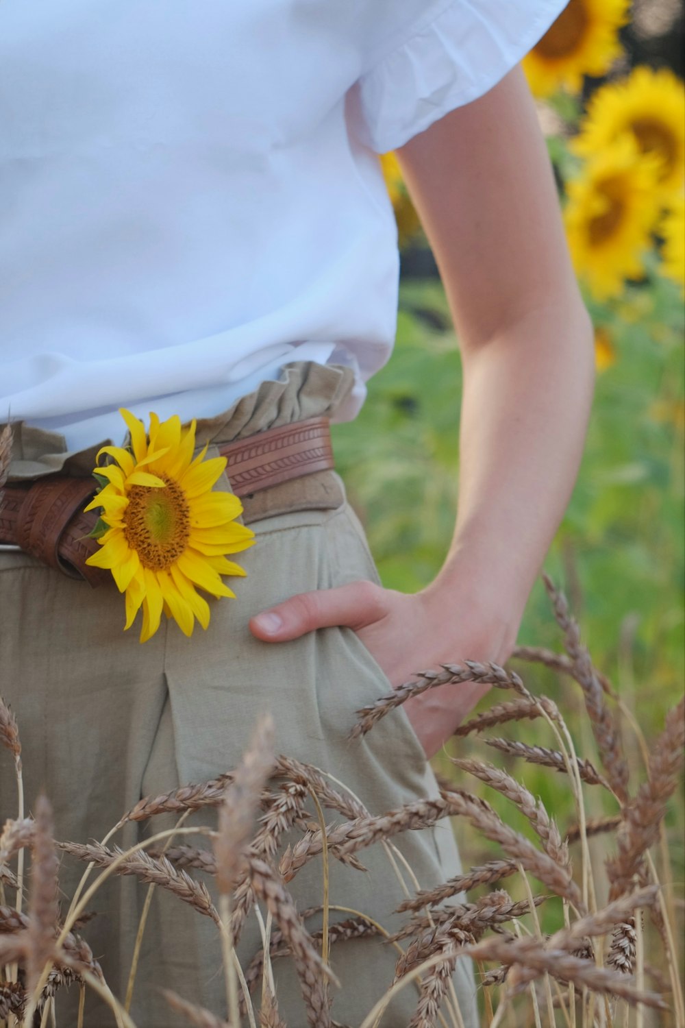 woman in white sleeveless dress holding yellow and white flower