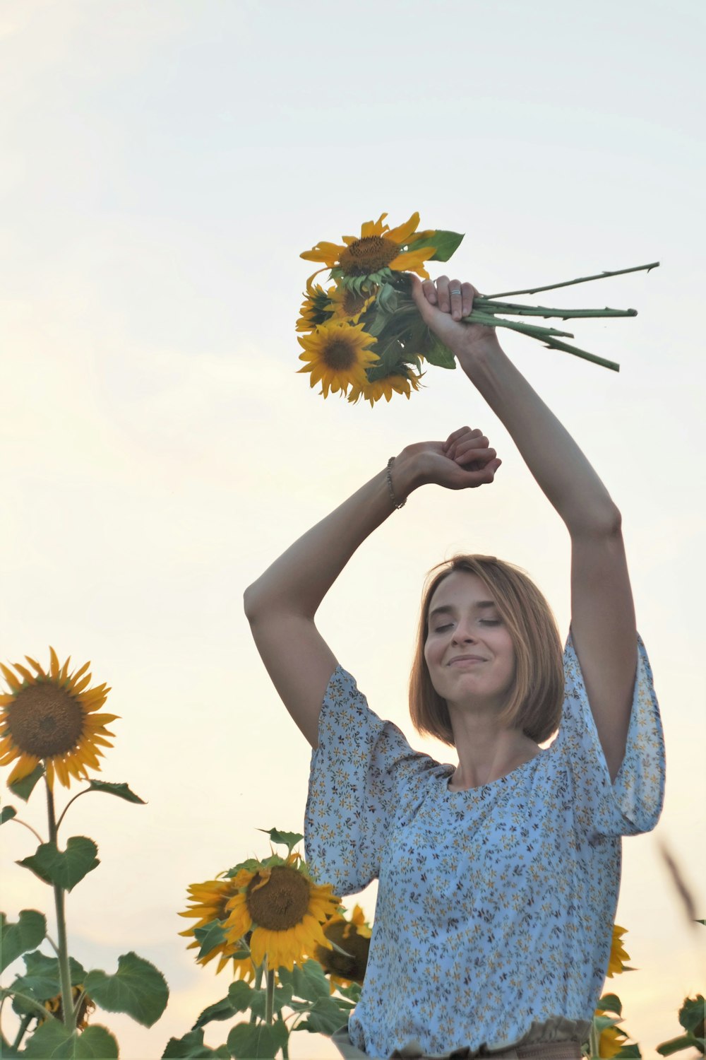 ヒマワリを持った青と白の花柄のドレスを着た女性