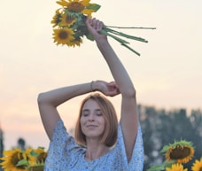 woman in blue and white floral dress holding sunflower