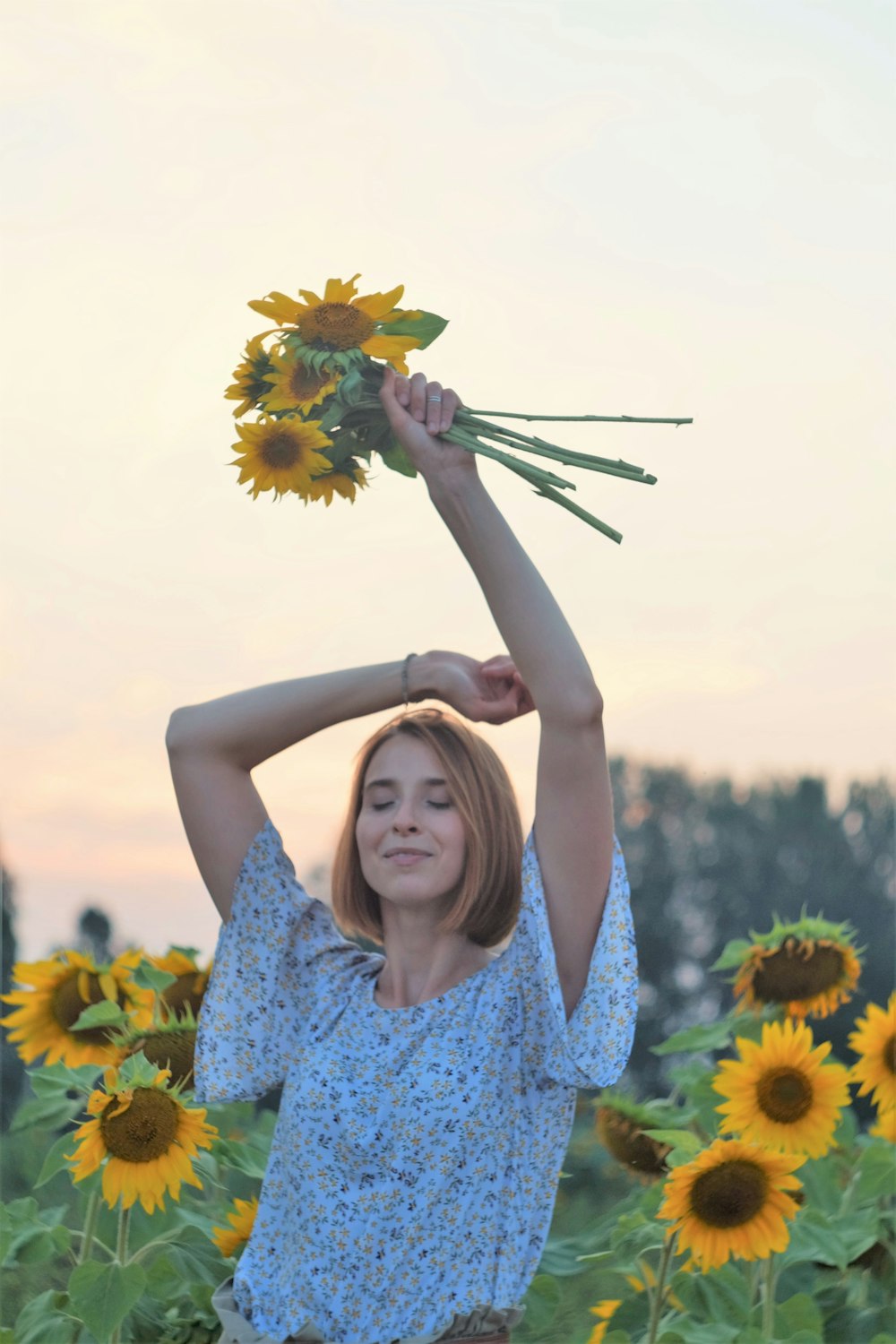woman in blue and white floral dress holding sunflower