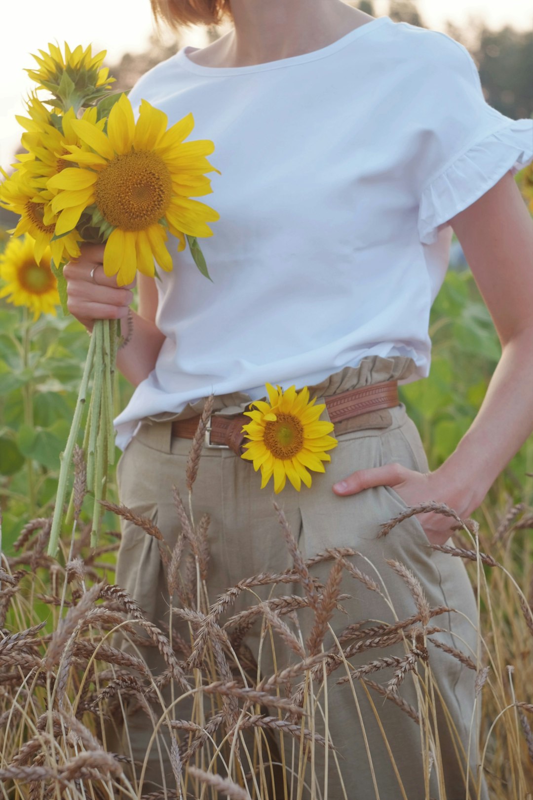 woman in white t-shirt and brown skirt holding yellow sunflower