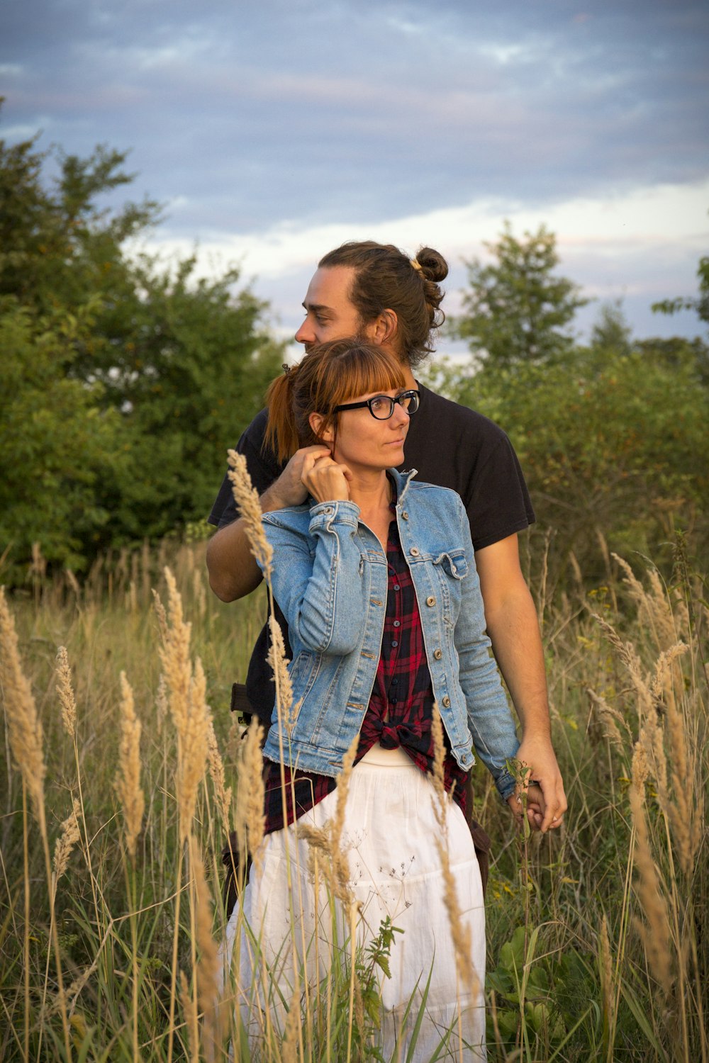 man in black crew neck t-shirt and woman in white dress standing on brown grass