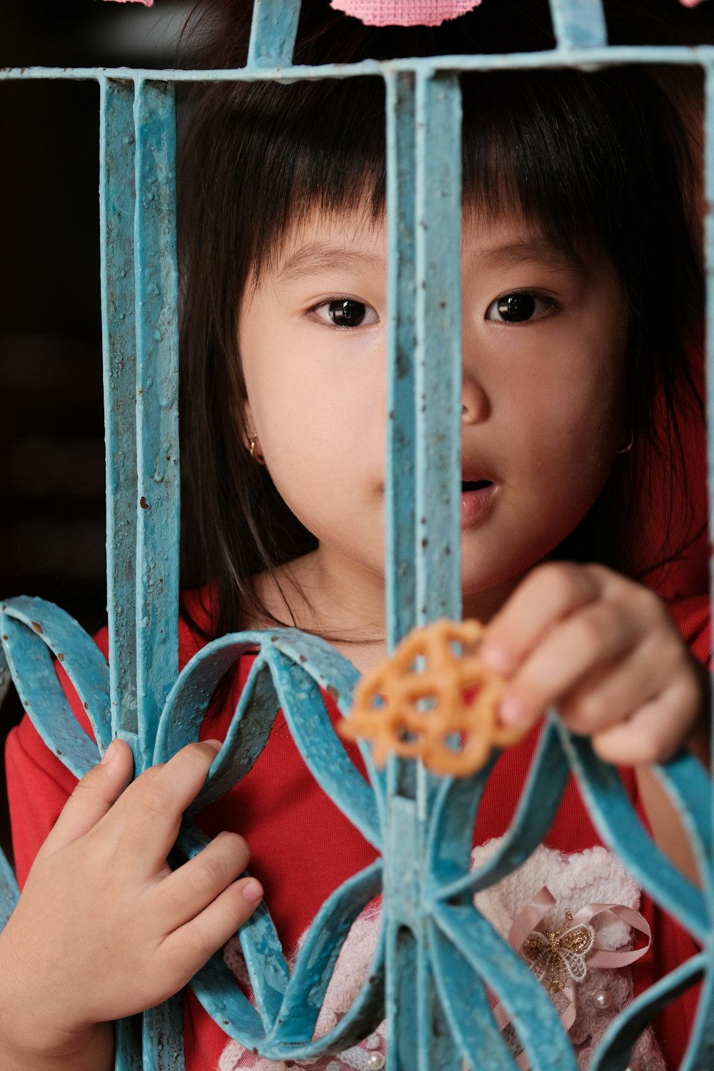 girl in red and white stripe shirt holding blue metal fence